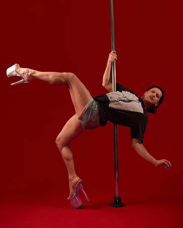 Luna em movimento de pole dance sobre fundo vermelho